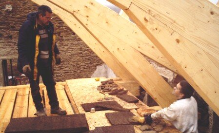 Enrique Banet, a la izquierda, hablando con Luis Sotelo mientras trabajan en la restauración de la cubierta de la escuela de Leboso